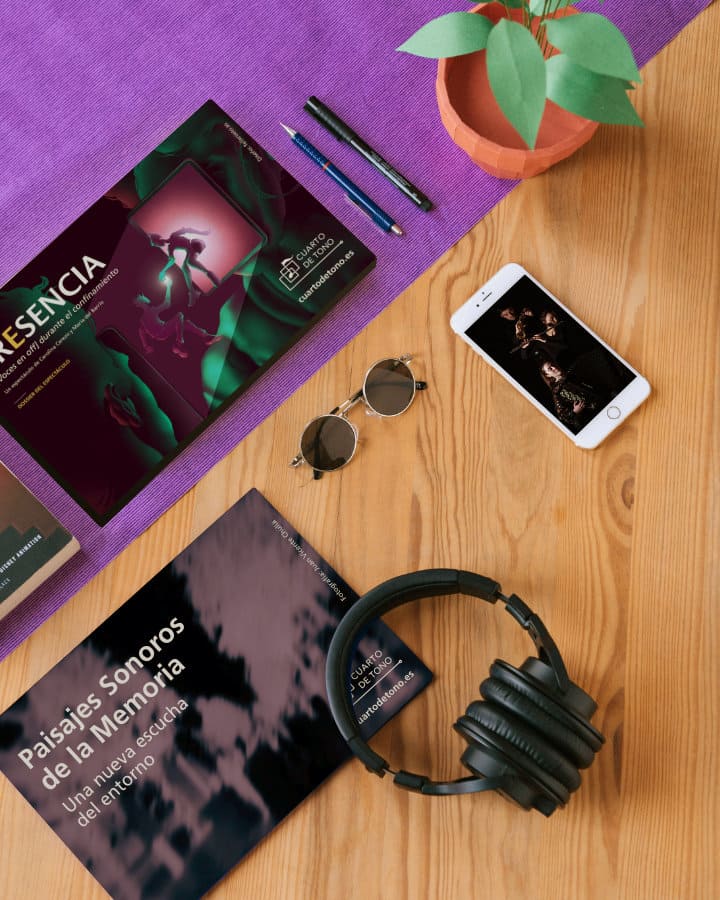 Table with various documents and a device showing the design of 'Cuarto de Tono', including headphones.