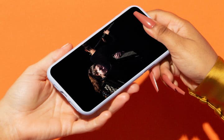 Person passing a mobile phone to another person showing a close-up image of two members of the Cuarto de Tono ensemble.