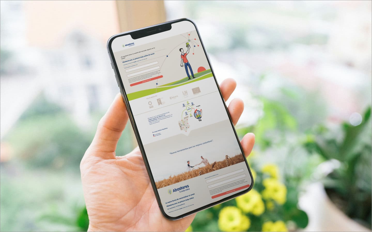 Mano de una persona aguantando un móvil en el que aparece la web de Abastores con formularios, explicación sobre la empresa y la identidad visual de la marca. En el fondo hay plantas y tonos verdosos relacionados con Abastores.