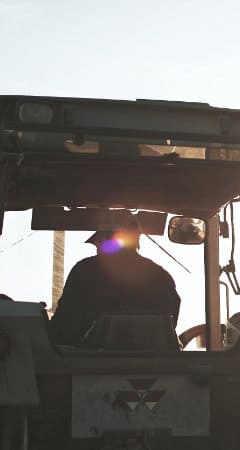 Silueta de un agricultor manejando una cosechadora al atardecer.